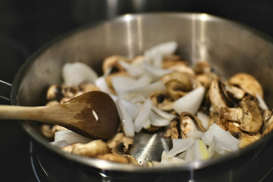 Cogumelos dourando na panela com colher de pau
