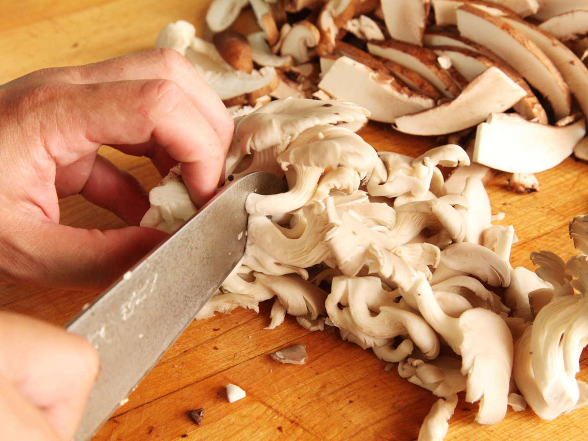 Cogumelos sendo picados na tábua para o recheio do gyoza