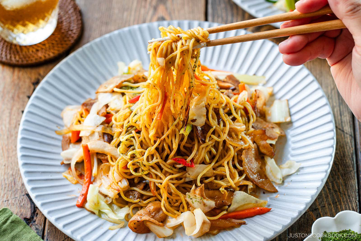 Yakisoba de shimeji servido no prato fundo com legumes e hashi ao lado